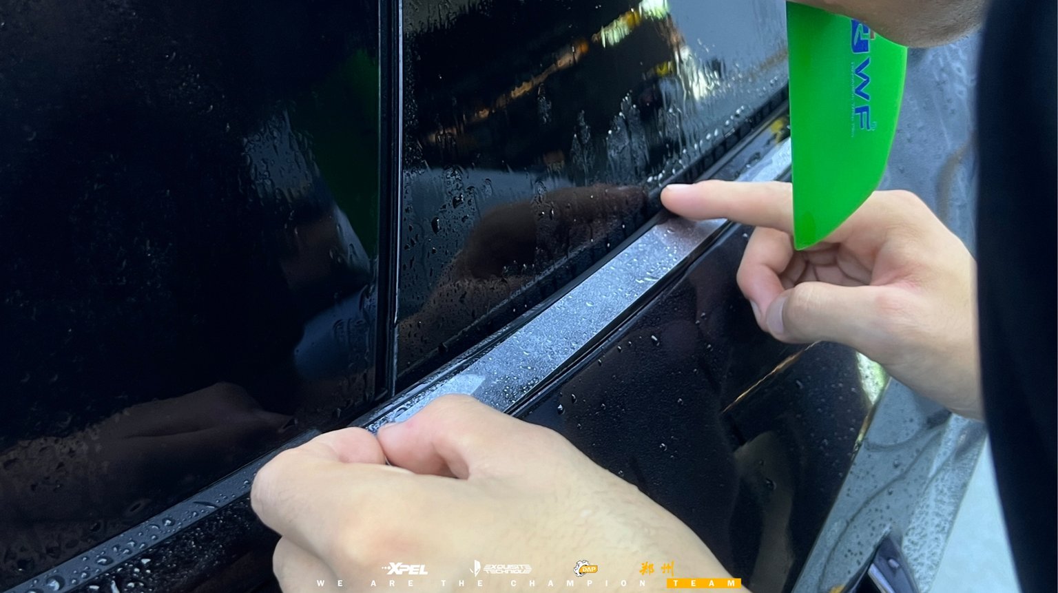 技师用绿色刮板在奥迪 A7L 车门处贴合膜体