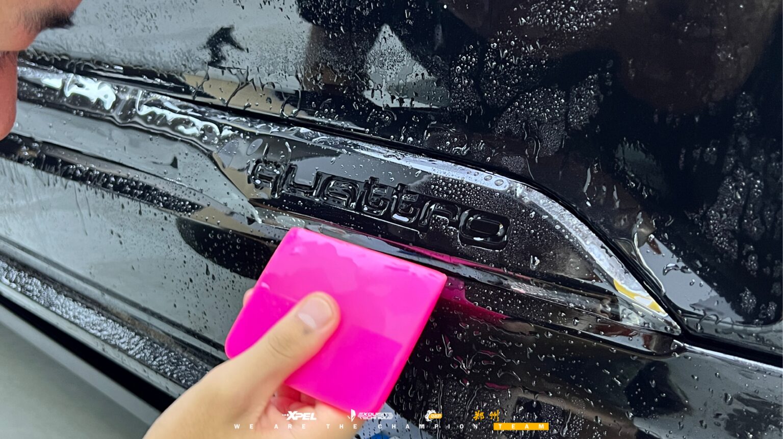 技师在奥迪 Q7 轮眉处贴膜收边,可见湿膜与刮板