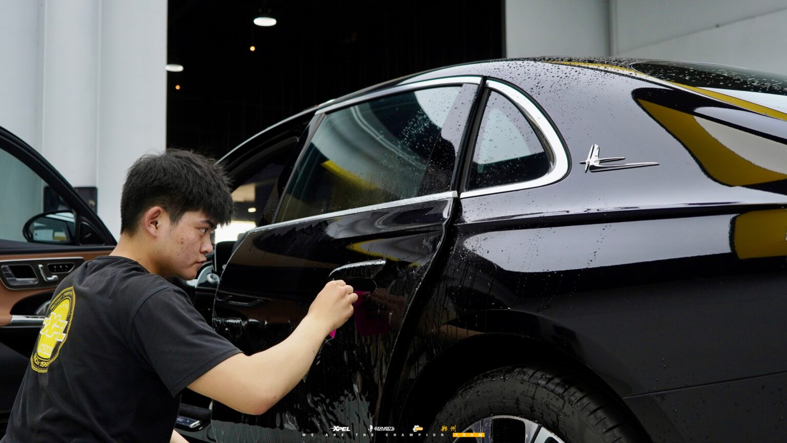 技师在奔驰 E300 后翼子板贴合膜体,镀铬饰条清晰
