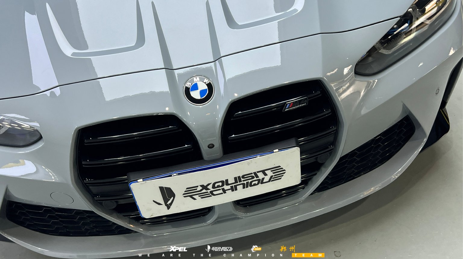 宝马 M4 双肾格栅与 BMW 车标特写,灰蓝色车漆光泽均匀