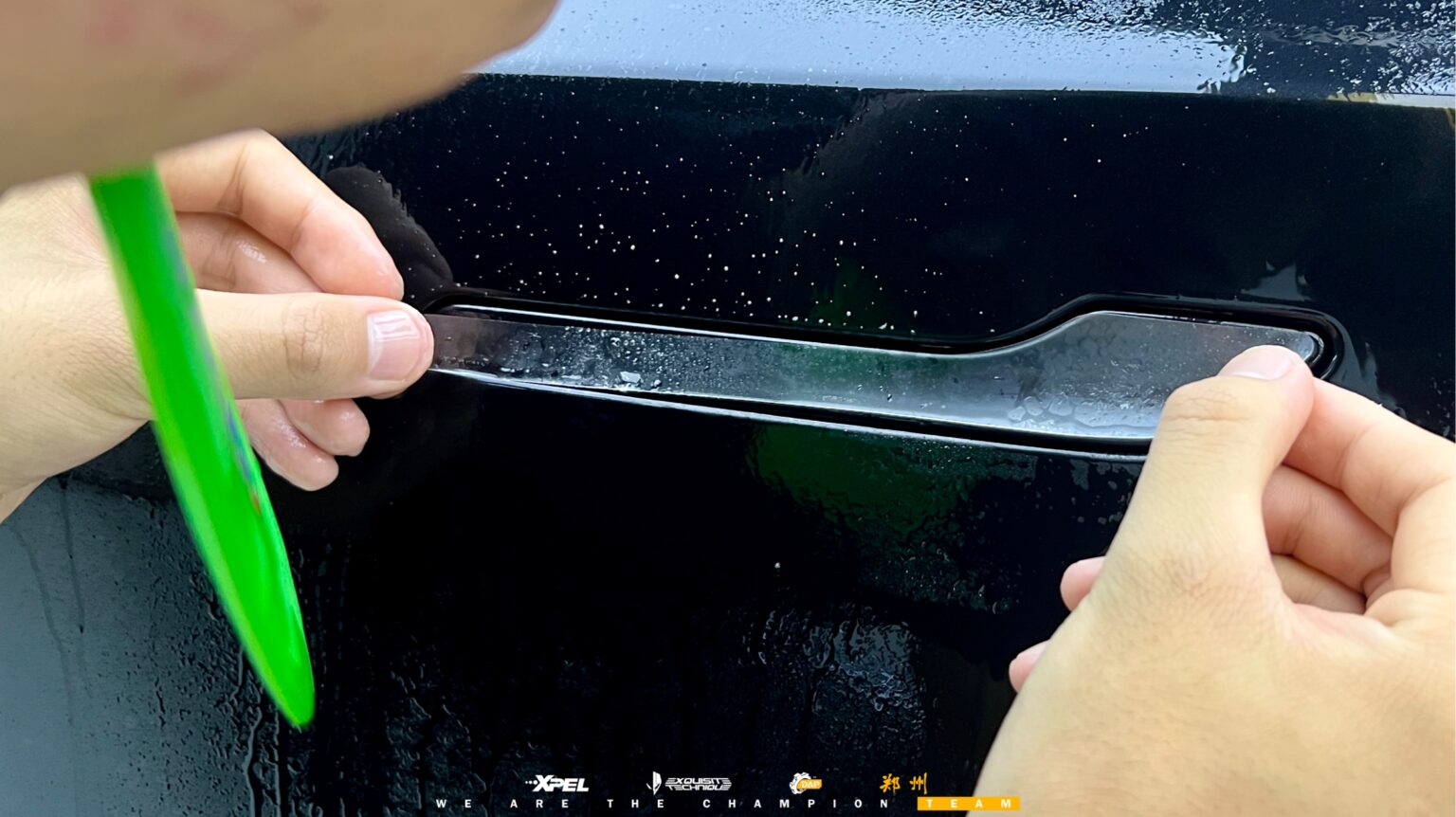 技师用绿色刮板在特斯拉 Model Y 后翼子板推压膜体