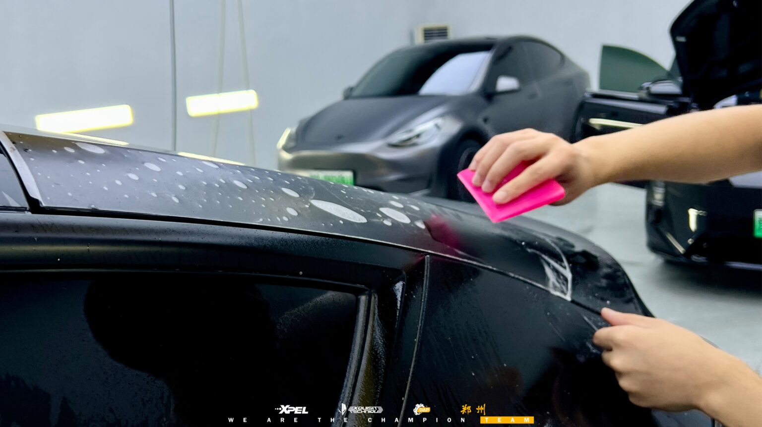技师用刮板在特斯拉 Model Y 门板处压实膜体