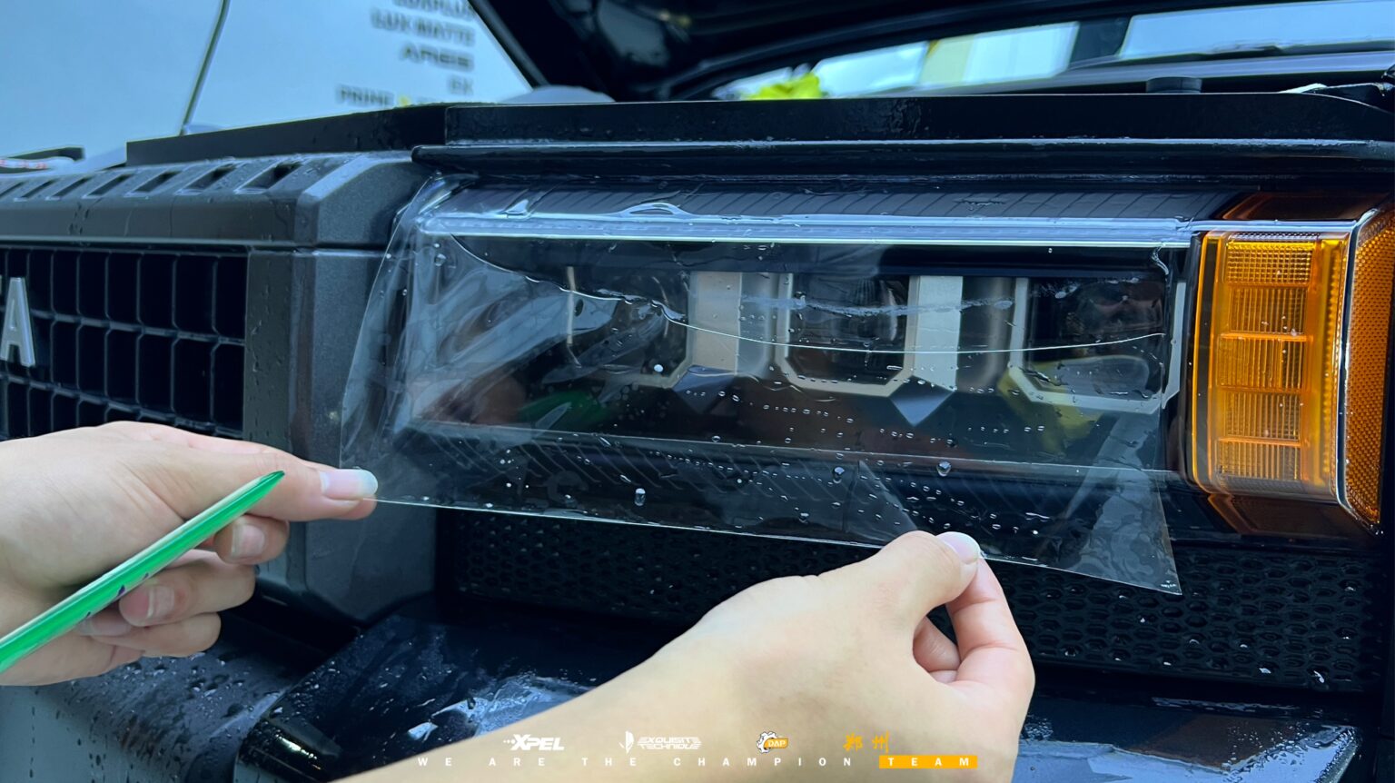 技师在丰田普拉多前格栅处贴膜，可见橙色大灯
