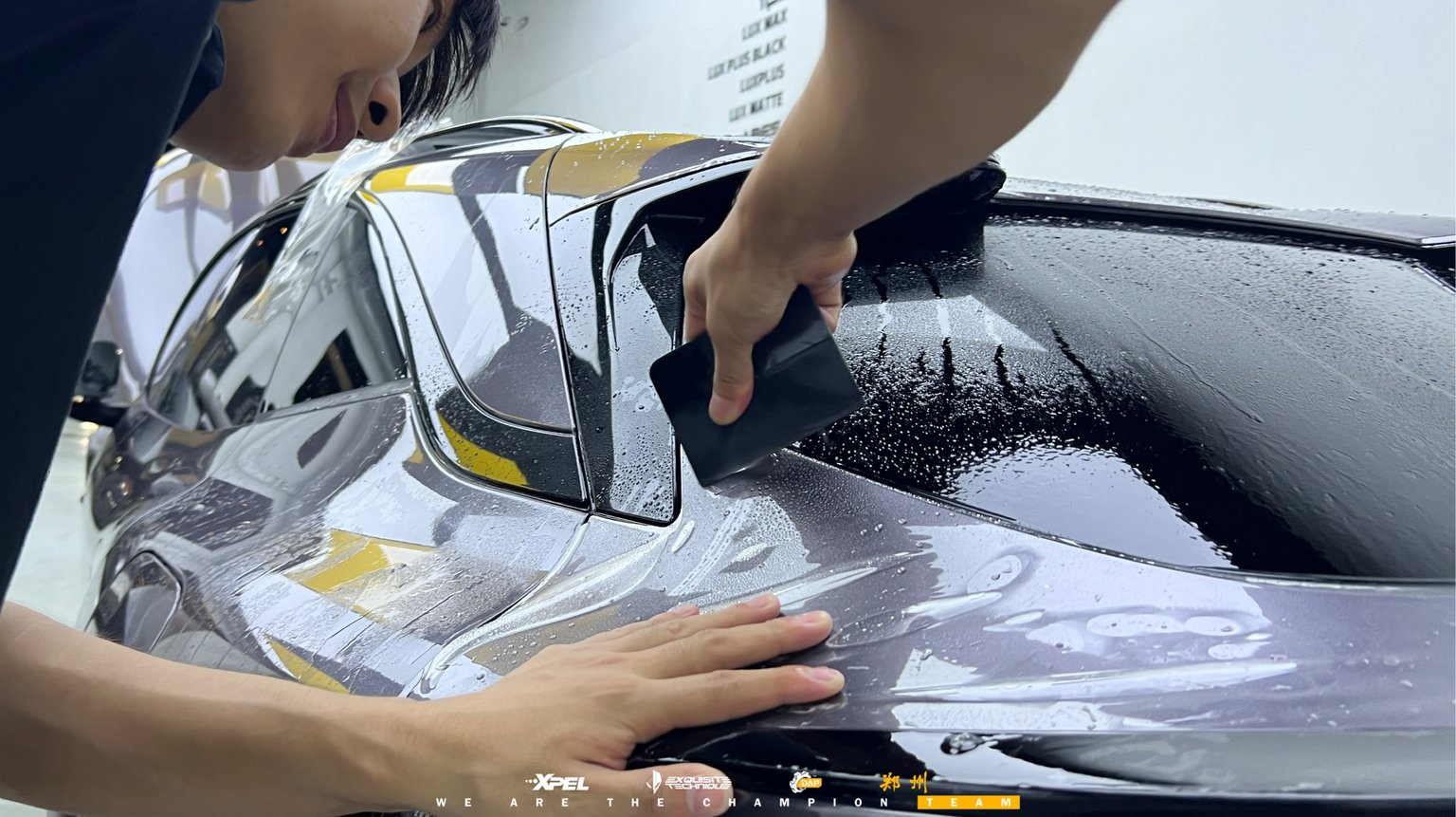 技师在极氪 007GT 车身铺展 XPEL 隐形车衣膜体,湿膜大面积可见