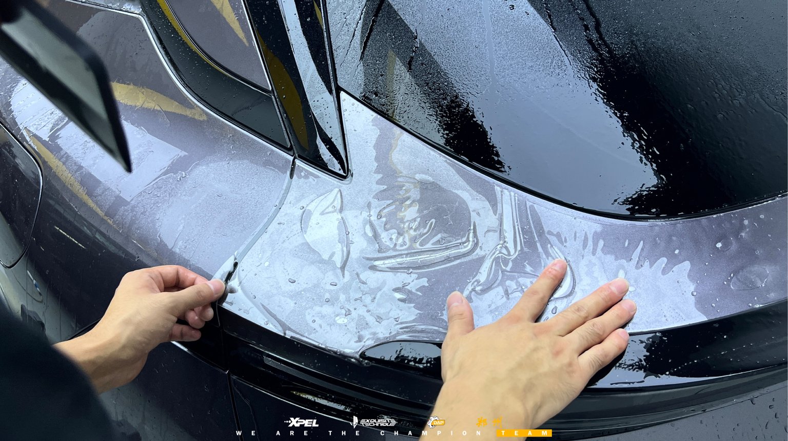 技师双手在极氪 007GT 门板处贴合膜体,膜面水痕清晰